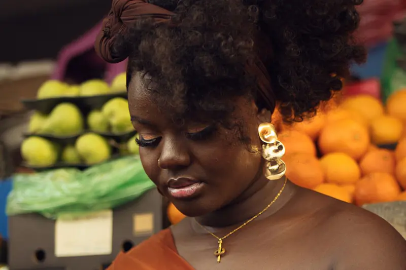 Commerçante sur un marché, devant un étal de fruits
