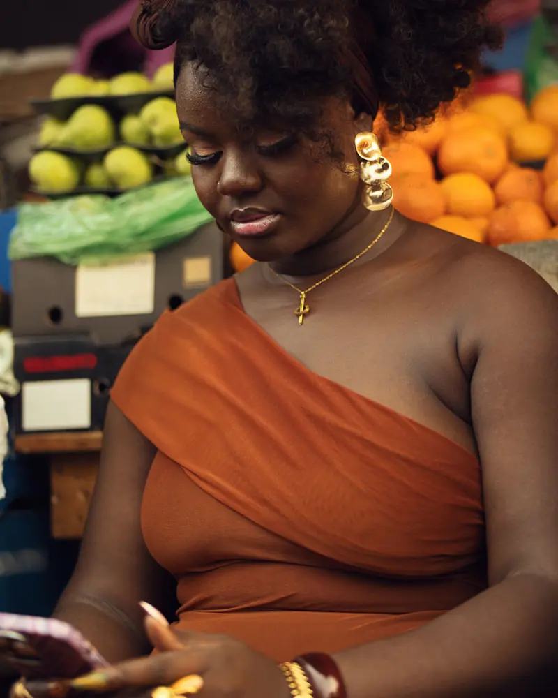 Commerçante consultant son téléphone devant son étal de fruits