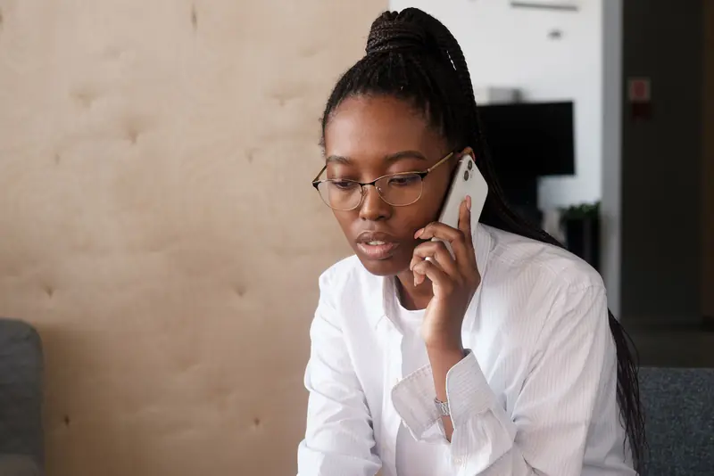 Femme en chemise blanche au téléphone, assise dans un espace de bureau
